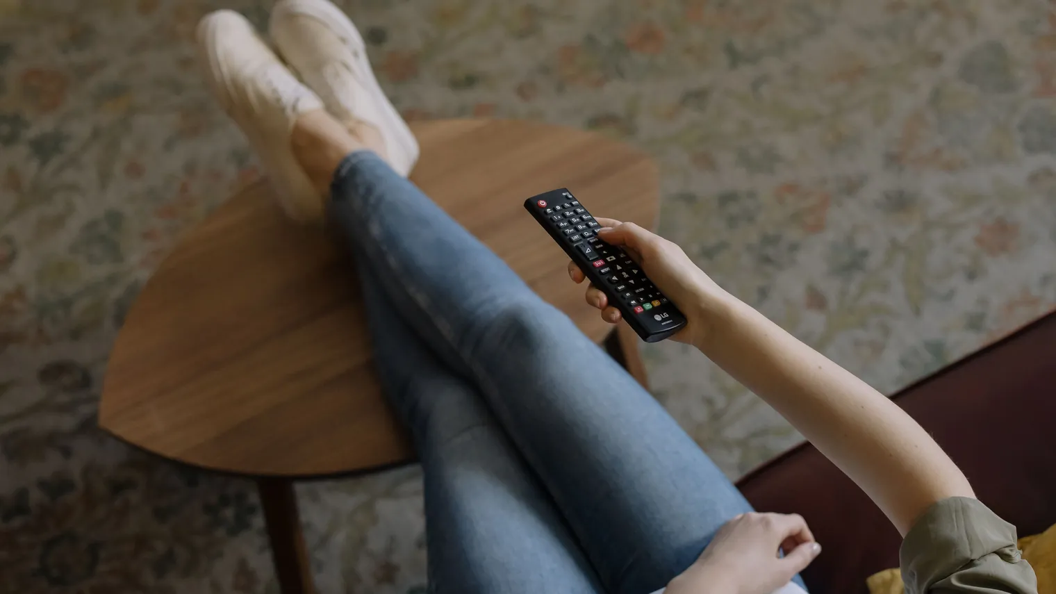 Person mit Fernbedienung am Abend auf dem Sofa